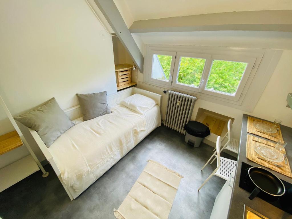 a small bedroom with a bed and two windows at STUDIO proche commodité et gare . Centre ville in Caen