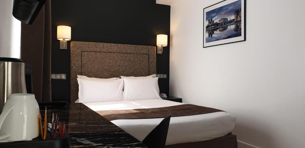 a hotel room with a bed with white sheets and pillows at Acacias Etoile in Paris