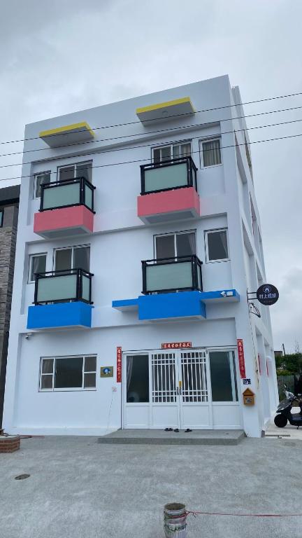 - un bâtiment blanc avec des balcons sur le côté dans l'établissement Murakami Travel Guest House, à Huxi