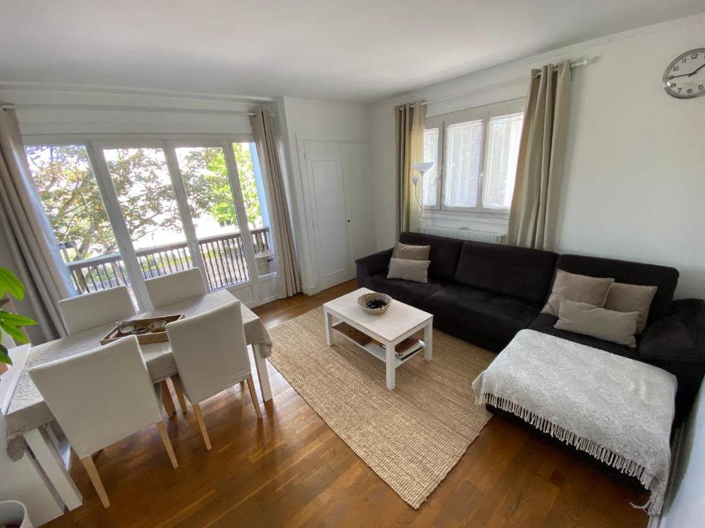 a living room with a black couch and a table at Belle Appartement lumineux avec balcon plein centre . in Caen