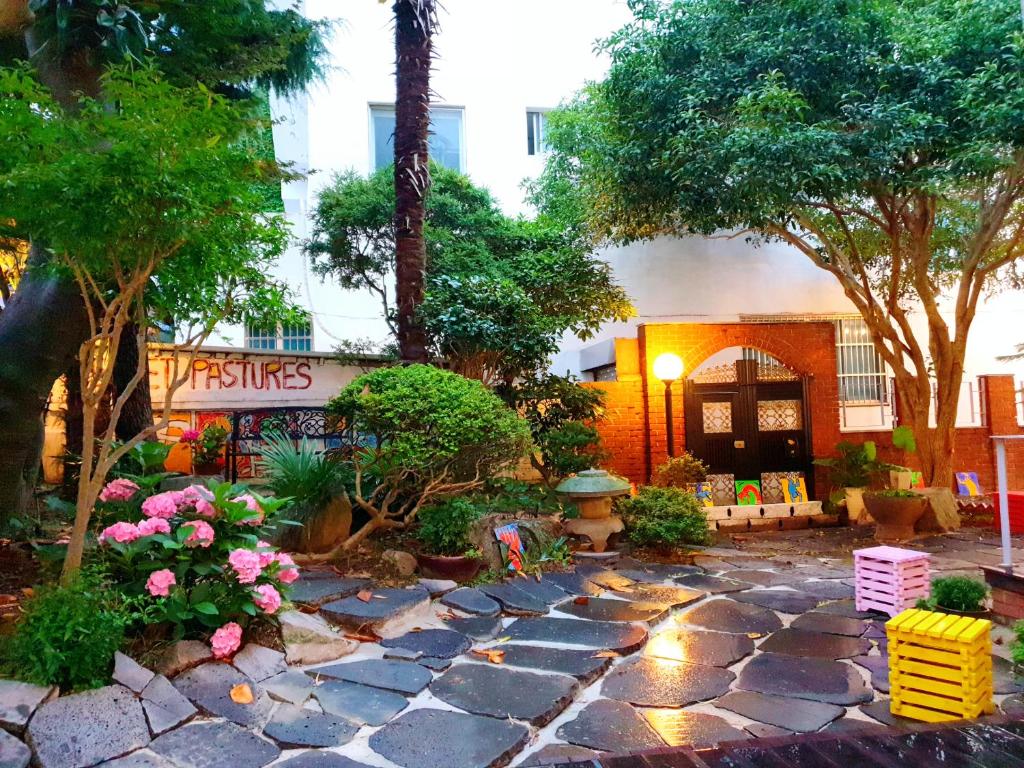 un jardín con una pasarela de piedra frente a un edificio en Gallery Family Hotel, en Mokpo