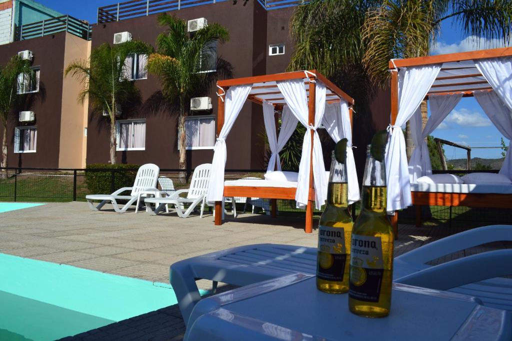 two bottles of beer sitting on a table next to a pool at Hotel Montana by CPH in Villa Carlos Paz