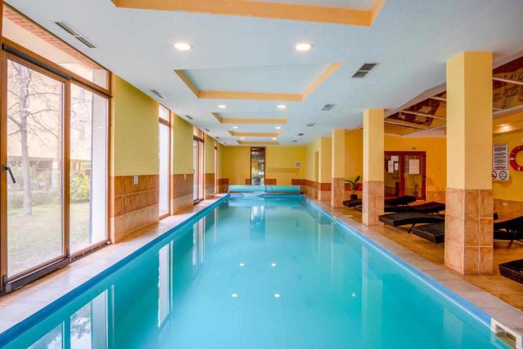 a swimming pool in a hotel with blue water at MyFlat Siófok Beach Wellness Apartment in Siófok