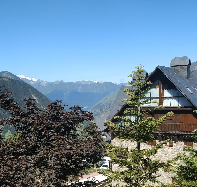 a building with trees and mountains in the background at Baqueira Apartamentos Cota 1700 tranquilidad in Baqueira-Beret