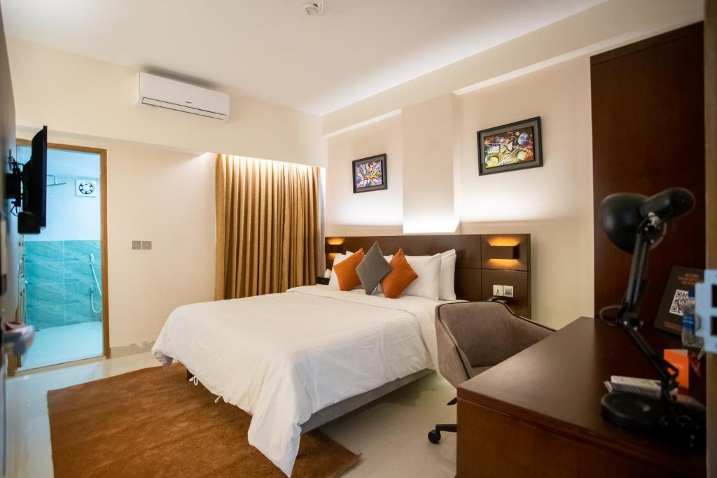 a hotel room with a bed, desk, and a television at Jatra Flagship Sylhet City Centre in Sylhet