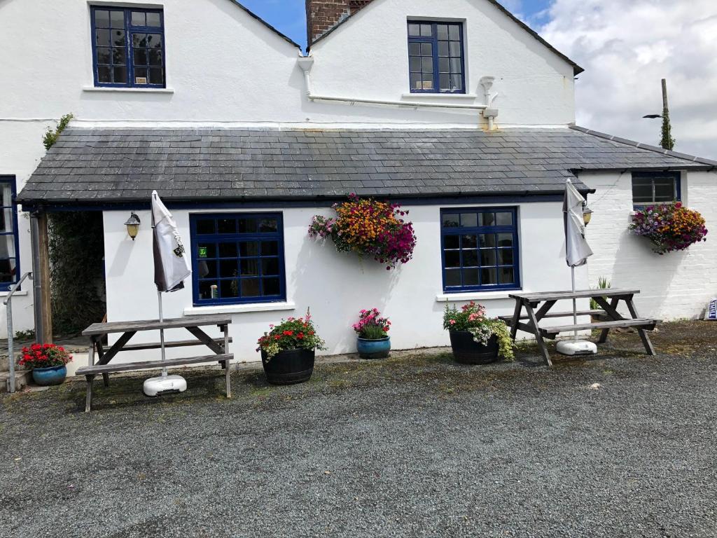 a white house with two picnic tables and flowers at Blue Lion Inn in Lewdown