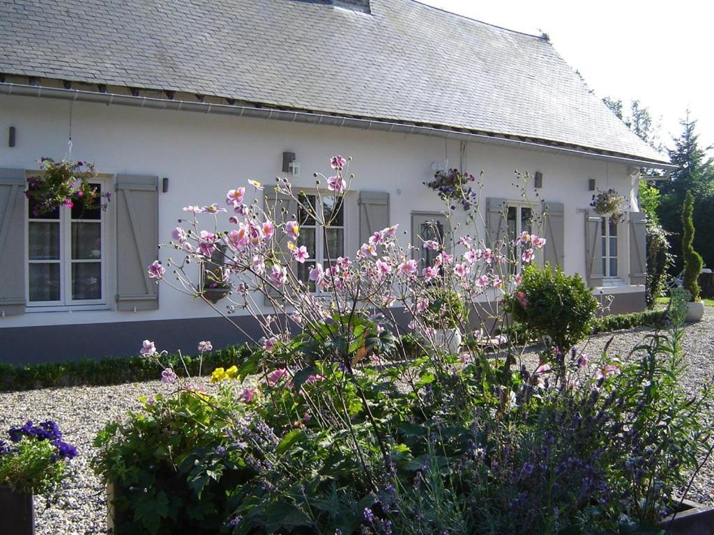 une maison blanche avec des fleurs devant elle dans l'établissement Gite Cottage d'Hamicourt aux Portes de la Baie de Somme, à Hamicourt