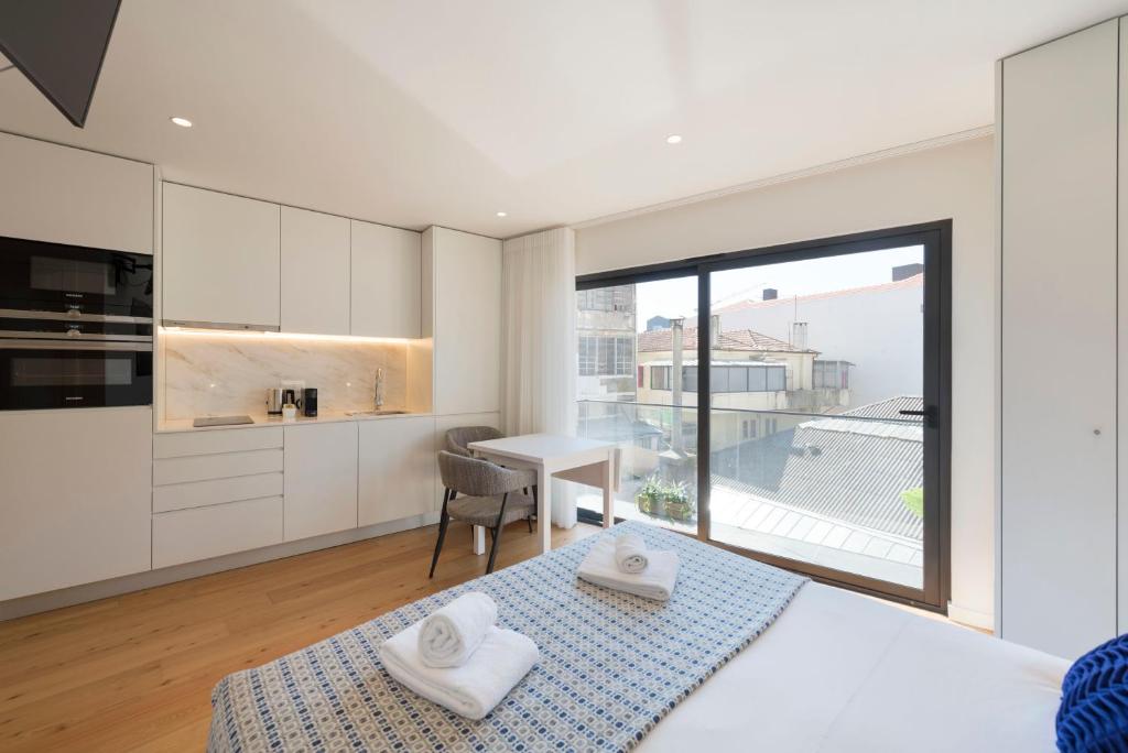 Cet appartement comprend une chambre avec un lit et une cuisine avec une fenêtre. dans l'établissement LovelyStay - Heart of D. Pedro Apartments IV, à Porto