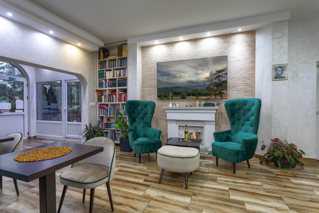 - un salon avec une cheminée et des chaises vertes dans l'établissement Guesthouse Dabić, à Zlatibor