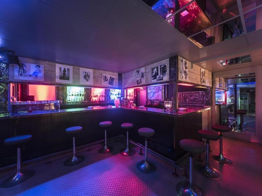 a bar with stools in a room with purple lighting at L'Usine in Belval