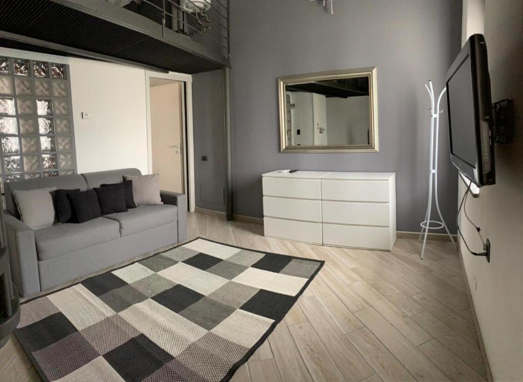 a living room with a couch and a mirror at APPARTAMENTO PIERANGELO DI FRONTE MALPENSA T1 e T2 in Vizzola Ticino