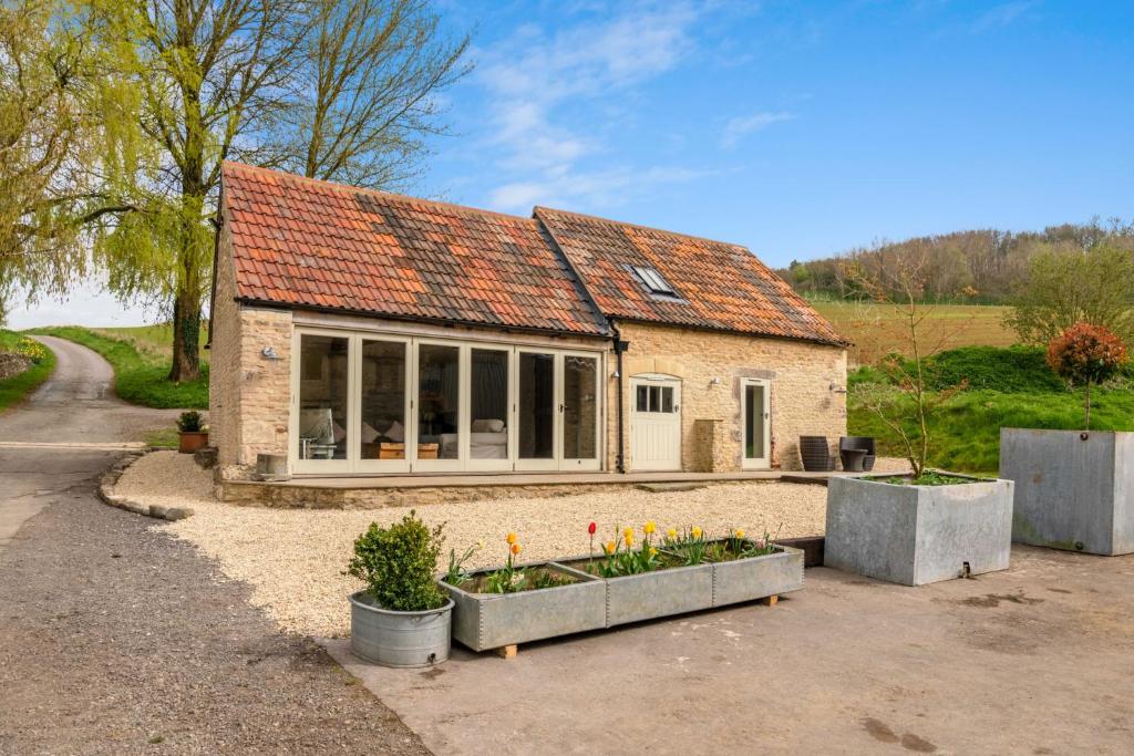 a small house with windows and flowers in front of it at Bull Pen in Dyrham