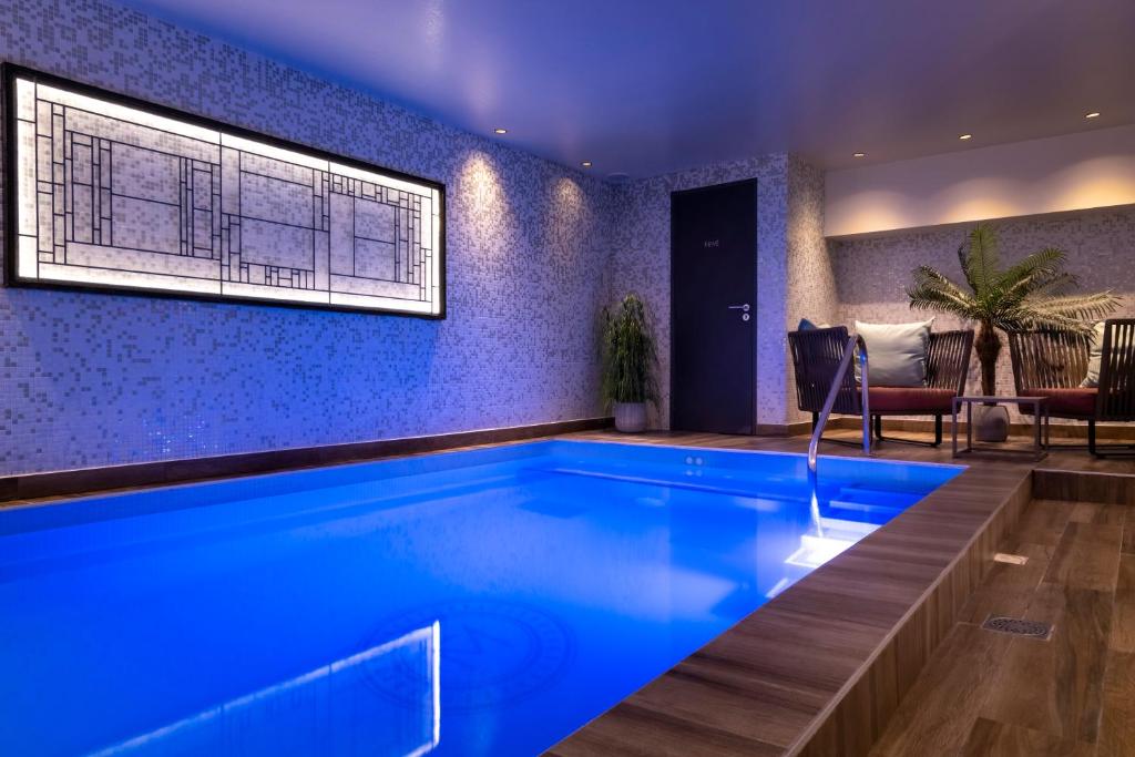 een zwembad in een woonkamer met blauwe verlichting bij Les Matins de Paris & Spa in Parijs