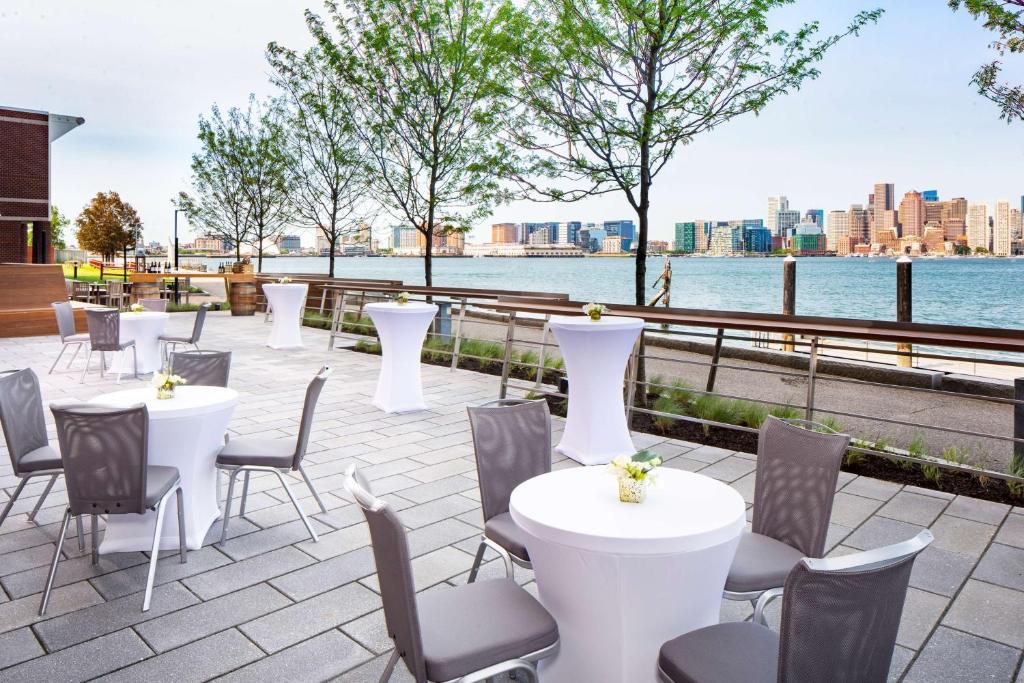 a patio with white tables and chairs and the water at Hyatt Regency Boston Harbor in Boston