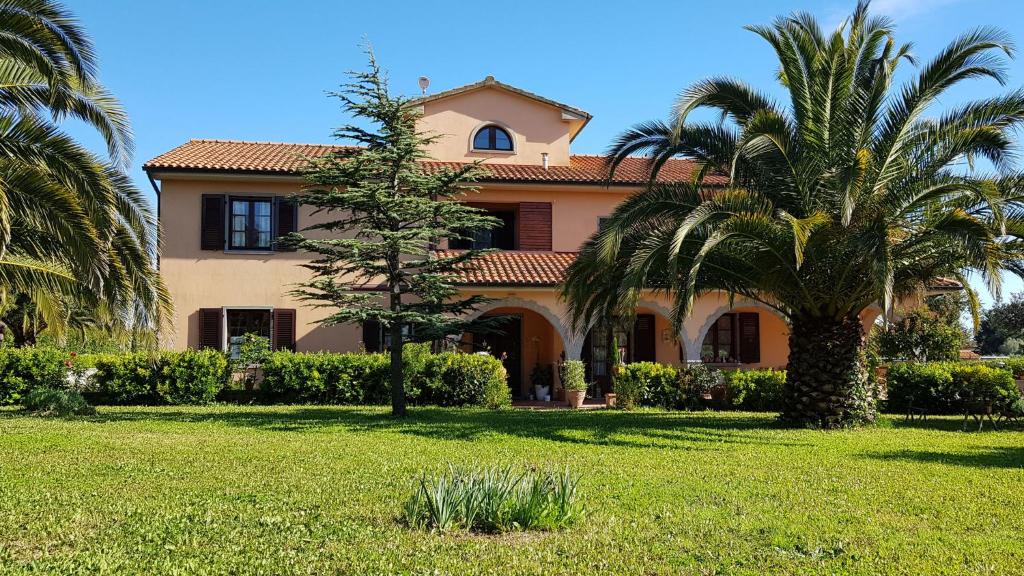 una casa grande con palmeras delante en Villa Mandrioli, en Cecina