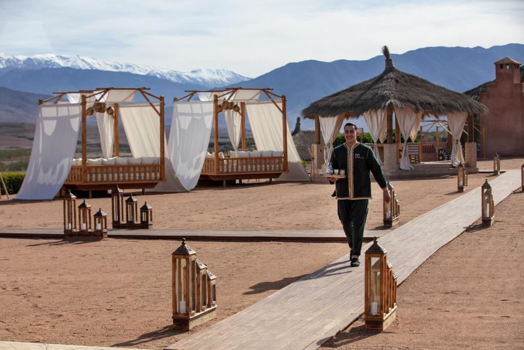 a man walking down a walkway with a row of tents at Kalyptus Luxury Camp in Lalla Takerkoust