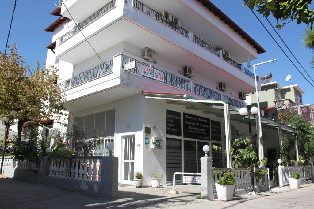 a white building with a balcony on a street at Lena Studios in in Hanioti