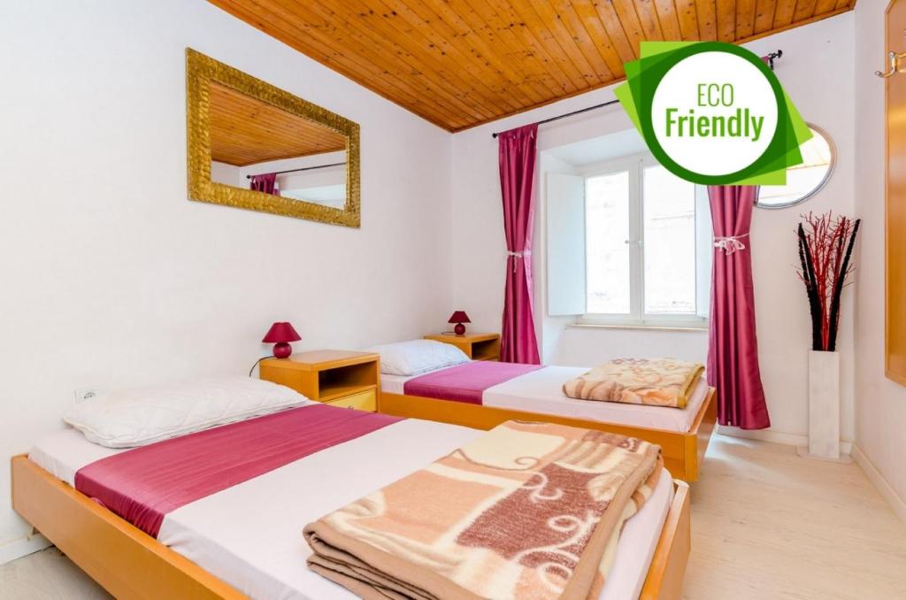 two beds in a room with a sign that says friendly at Rooms Jozomare in Dubrovnik