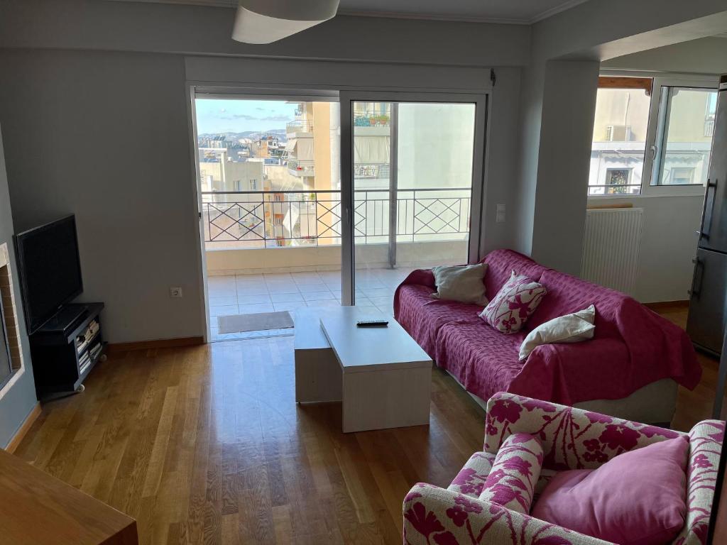 a living room with a purple couch and a balcony at ΔΙΑΜΕΡΙΣΜΑ ΜΕ ΘΕΑ in Athens