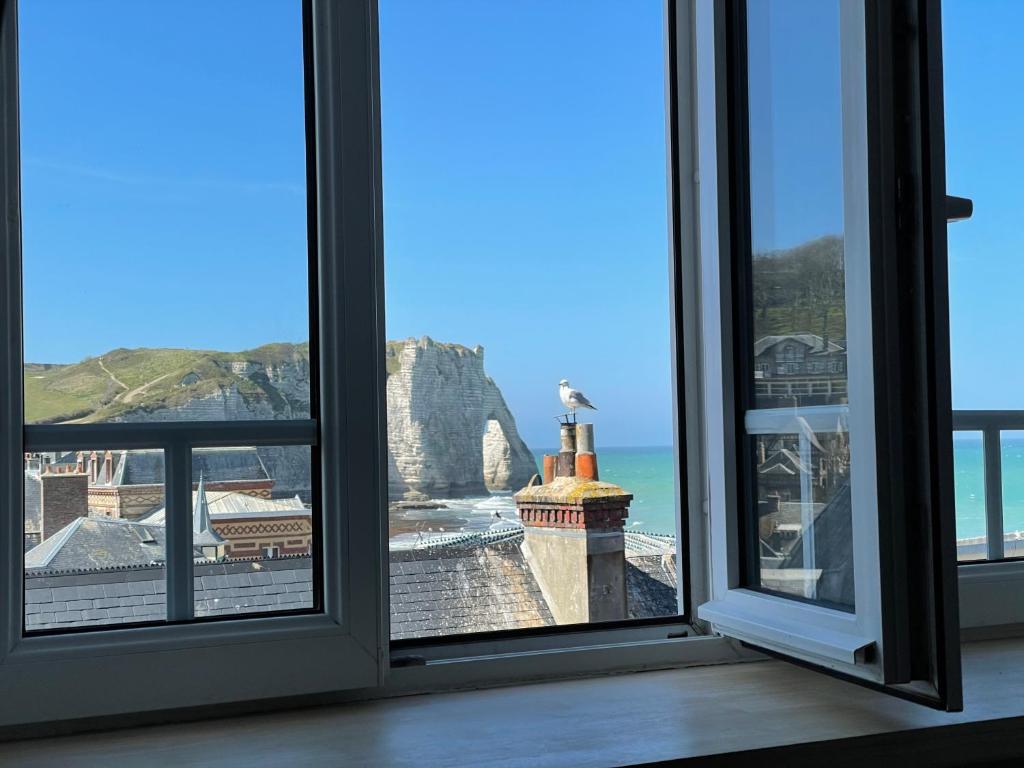 an open window with a view of the ocean at La Résidence - Vue falaise d'Aval in Étretat