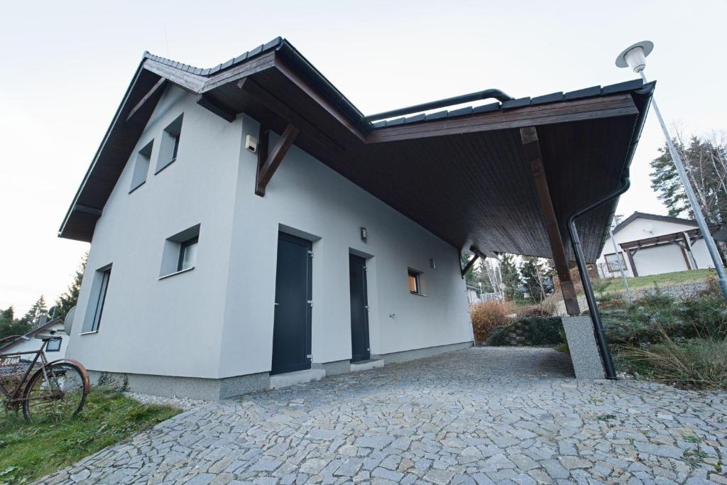伏爾塔瓦河畔利普諾的住宿－Holiday Lipno，一间小型白色房屋,设有太阳能屋顶