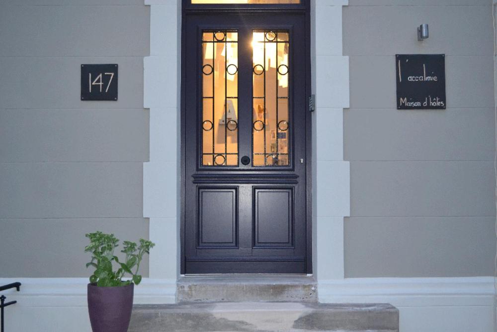 une porte noire sur un bâtiment avec une plante en pot dans l'établissement Villa l'Accalmie, à Wimereux