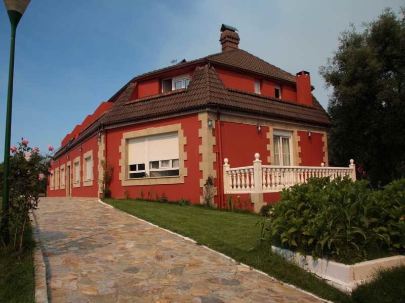 uma grande casa vermelha com uma cerca branca à volta em Arena Surf Hotel em Somo