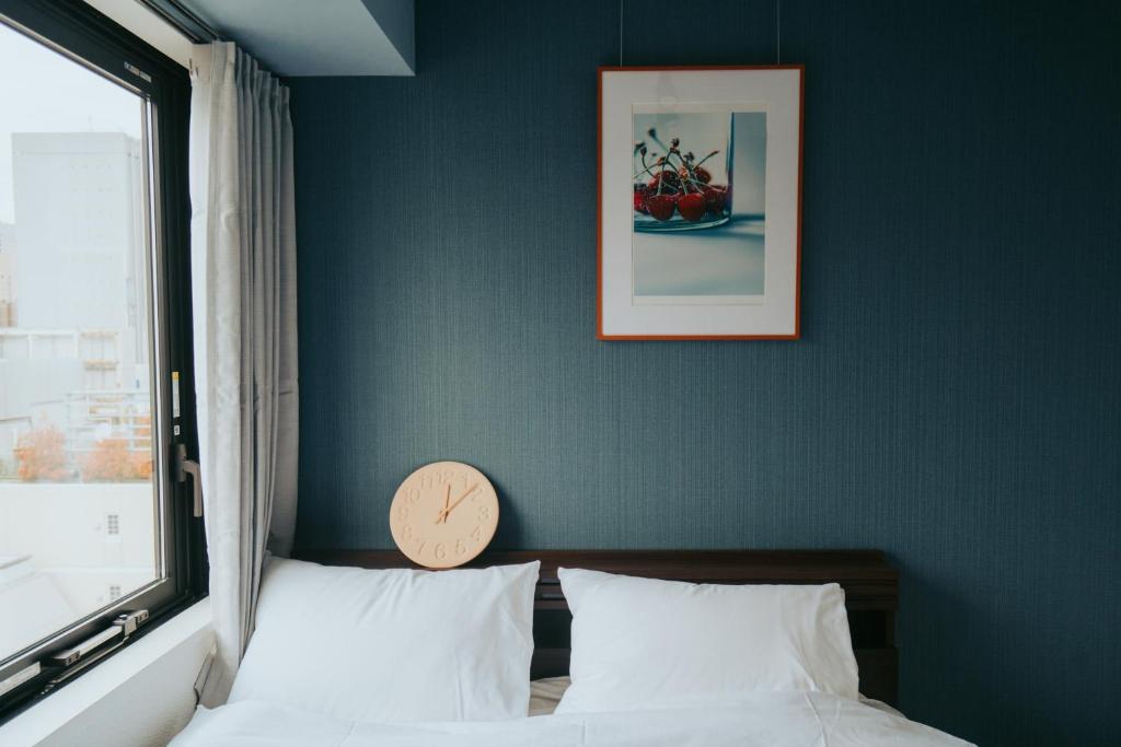um quarto com uma cama com um relógio na parede em unito SHIODOME em Tóquio