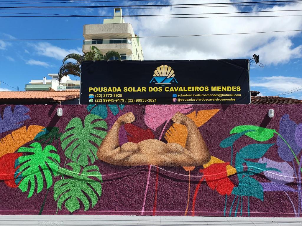 un panneau sur le côté d'un bâtiment avec une fresque murale dans l'établissement Pousada Solar dos Cavaleiros Mendes, à Macaé