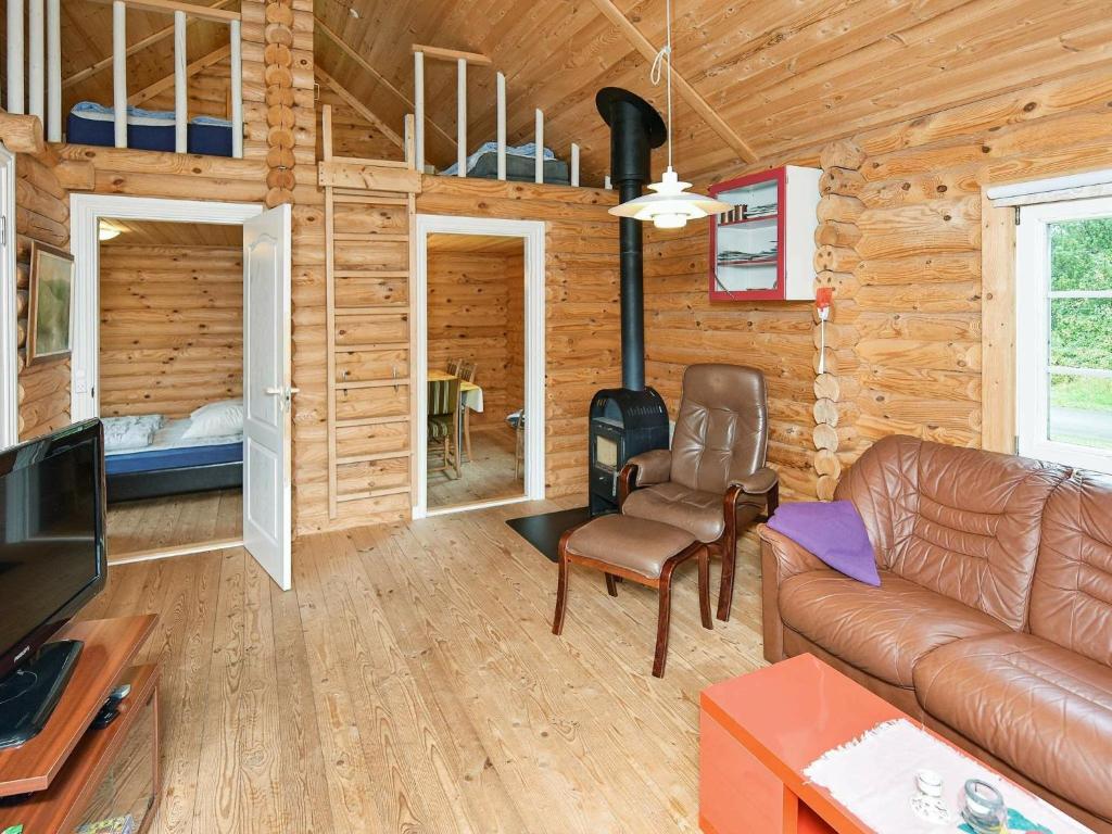 Cabaña de madera con sala de estar con sofá y chimenea. en Holiday Home Torpet VI, en Hovborg