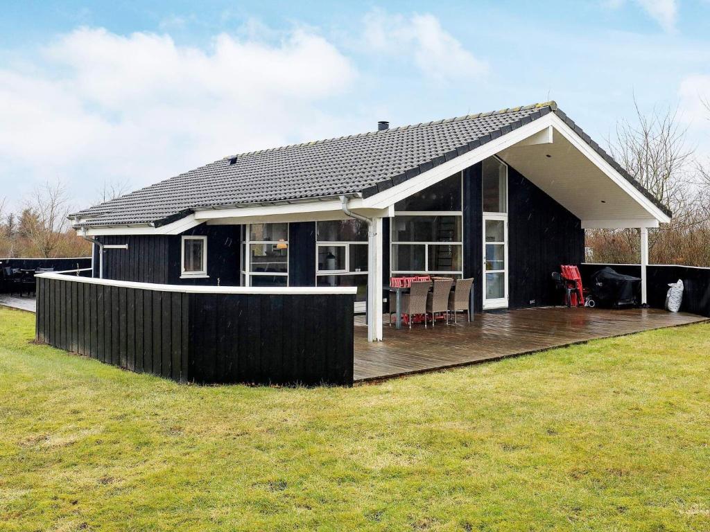 una casa negra con terraza en un patio en 6 person holiday home in L kken, en Løkken