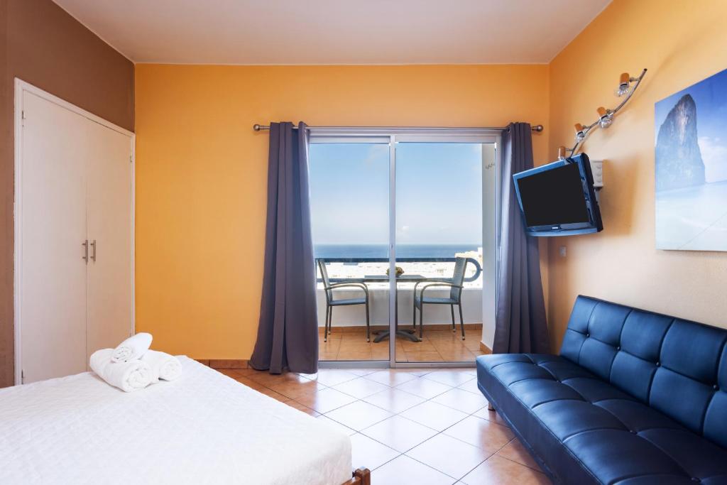 Habitación con sofá, TV y balcón. en Home2Book Cozy Apartment Playa Paraiso en Adeje