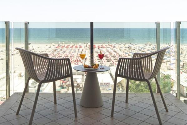 una mesa con dos sillas y dos copas de vino en Hotel Regina in spiaggia, en Rímini