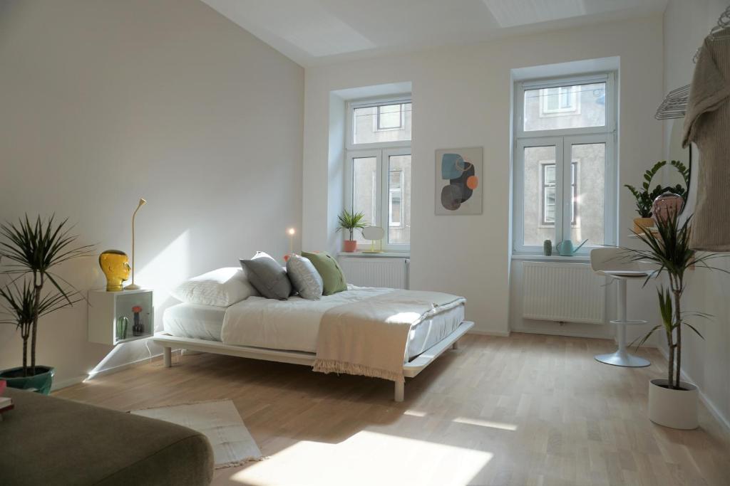 biała sypialnia z łóżkiem i dwoma oknami w obiekcie Modern 2Br Apartments - Full Kitchen - Schönbrunn Area - 15 Mins to City Center w Wiedniu