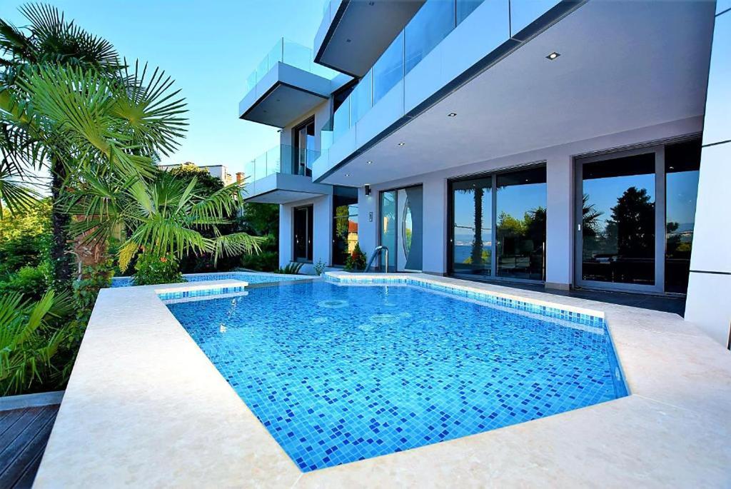 a swimming pool in front of a house at Apartments Marjanovic in Opatija