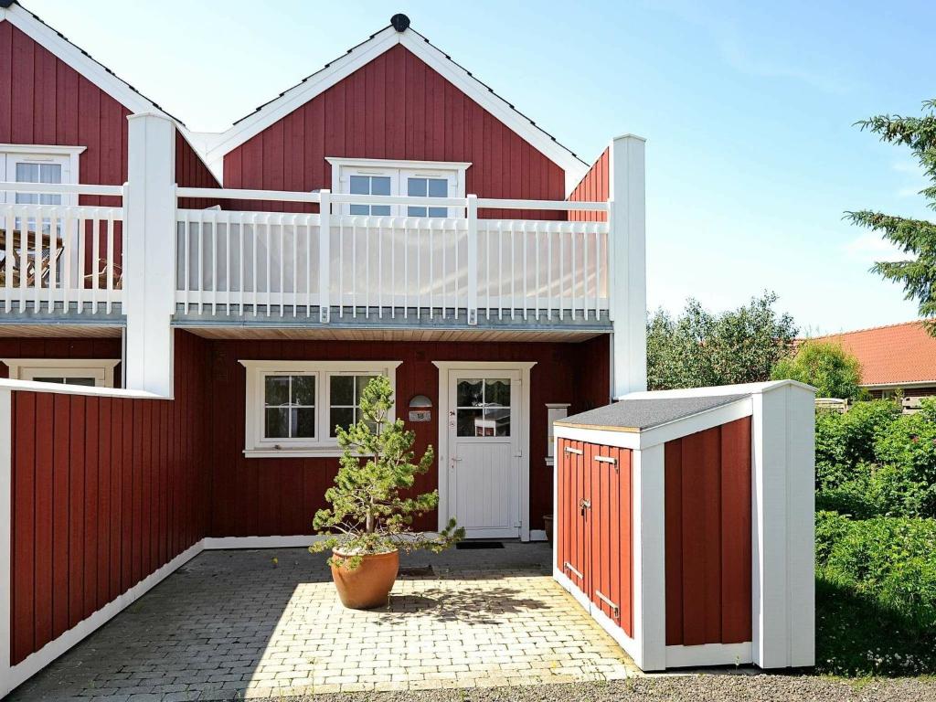 uma casa vermelha com uma varanda branca por cima em 4 person holiday home in Bl vand em Blåvand