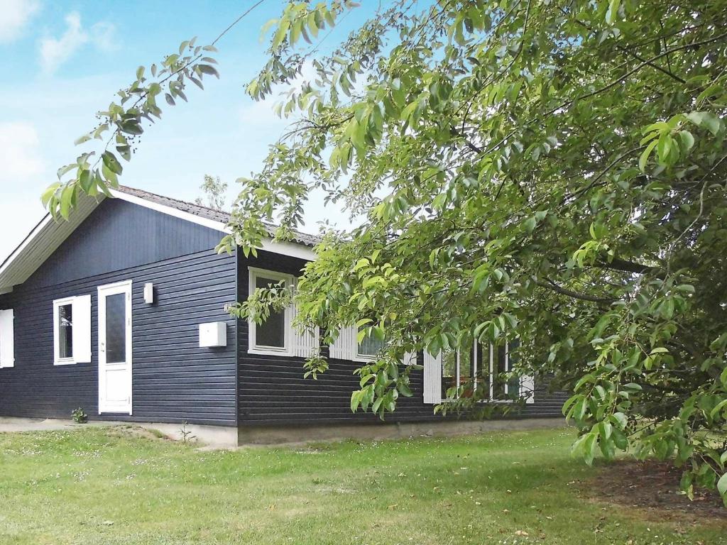 ノーポにあるThree-Bedroom Holiday home in Nordborg 3の白窓と木のある黒い家