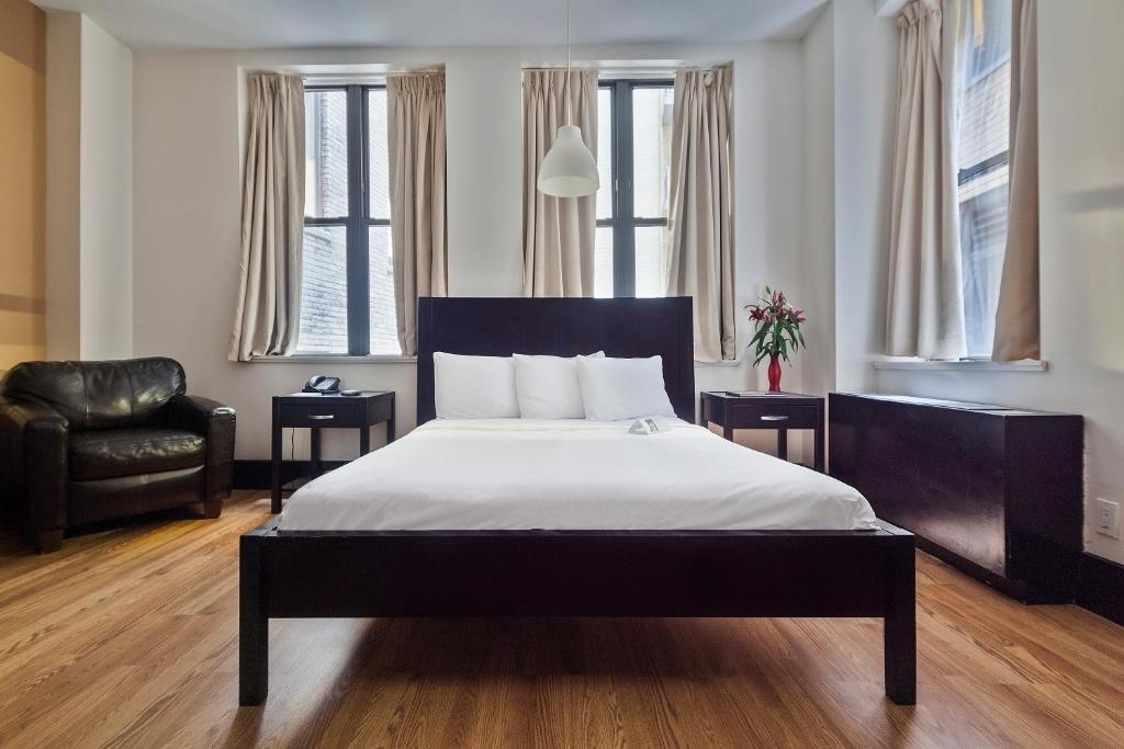 1 dormitorio con 1 cama, 1 silla y ventanas en Eurostars Wall Street, en Nueva York