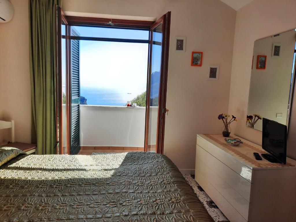 1 dormitorio con 1 cama y puerta corredera de cristal en L'Arabesco Apartment, en Amalfi