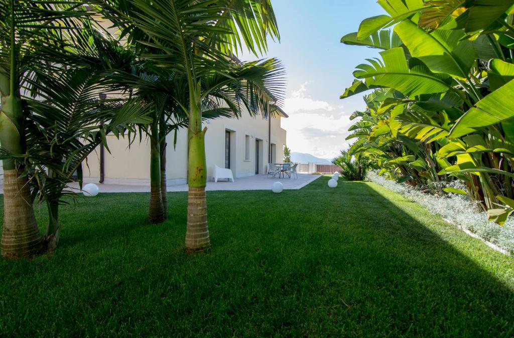 a yard with palm trees in front of a house at Alka Loft e Spa in Alcamo
