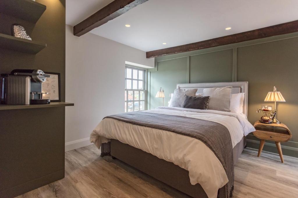 a bedroom with a large bed with green walls at The Ostrich Inn in South Creake