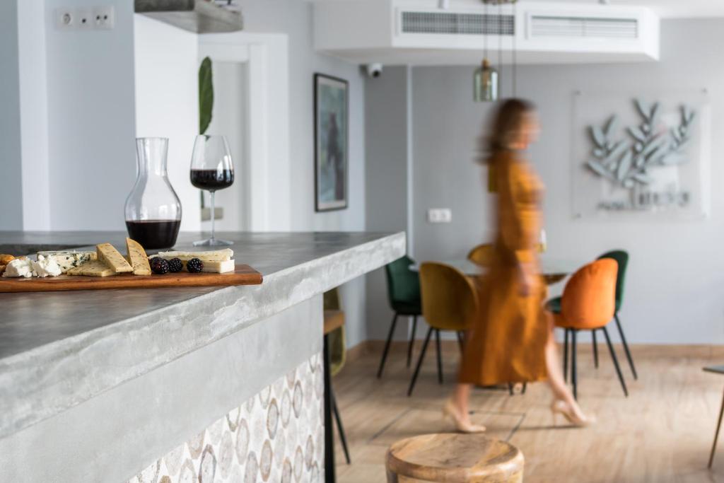 a woman walking past a counter with wine glasses at Linda Boutique Hotel in Marbella
