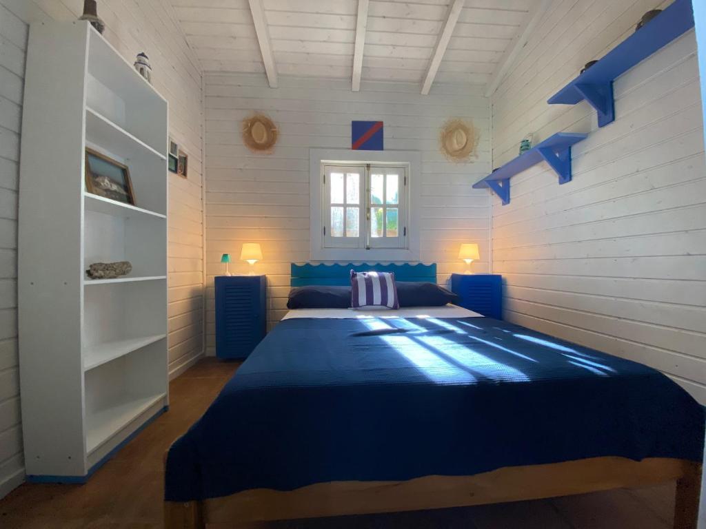 ein Schlafzimmer mit einem blauen Bett in einem weißen Zimmer in der Unterkunft Rustic Cabin Tarifa 4 guests 10 minutes to beach in Tarifa
