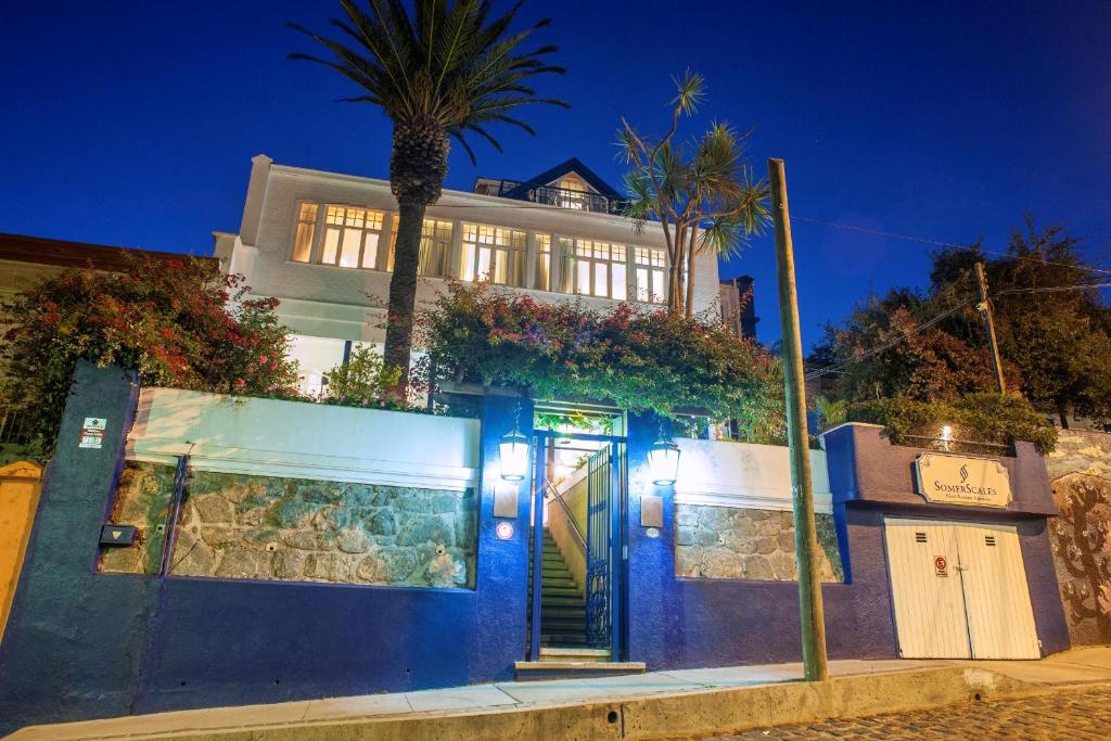 a house with a blue door and a palm tree at Hotel Casa SOMERSCALES in Valparaíso