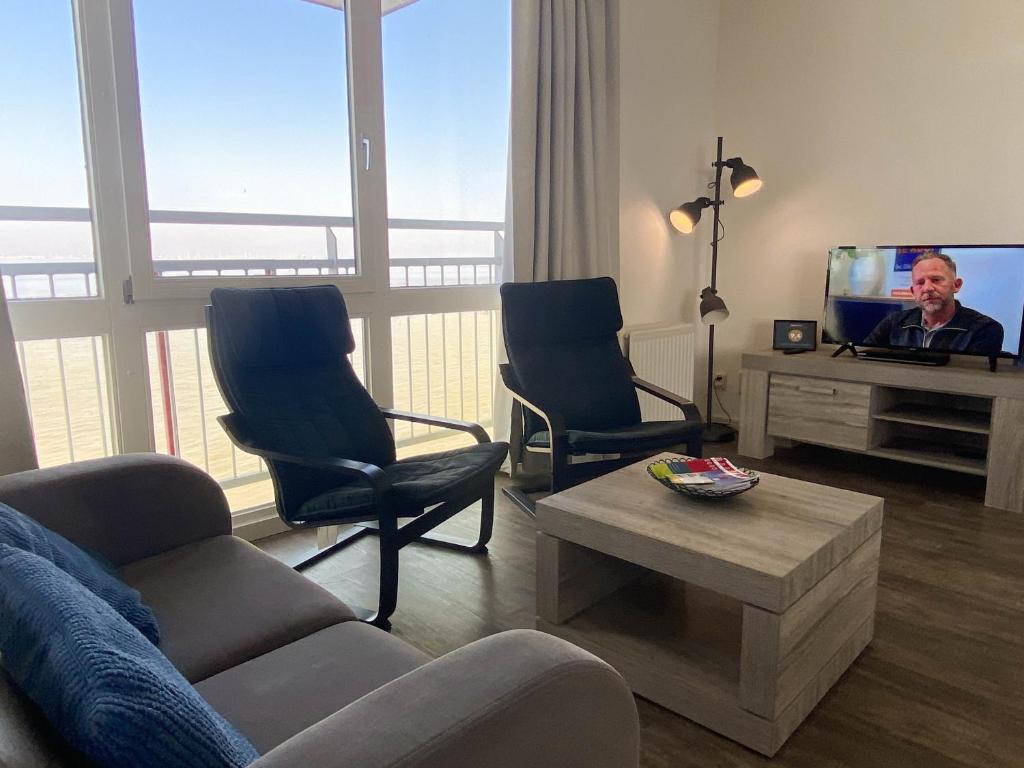 een woonkamer met een bank en stoelen en een tv bij Hello Zeeland - Appartement Port Scaldis 09-072 in Breskens