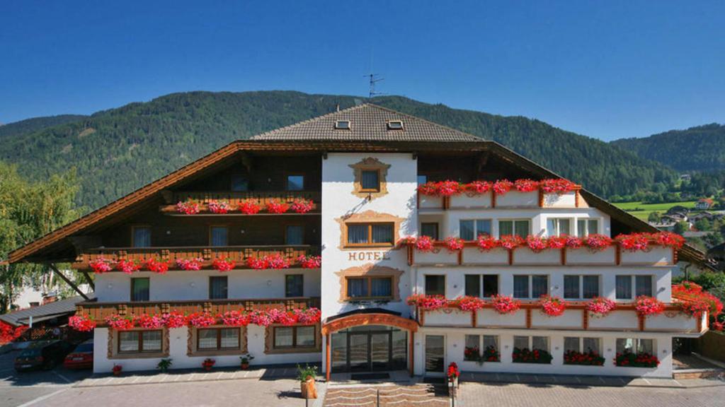 a large building with red flowers on it at Hotel Kronplatzer Hof in Rasun di Sopra