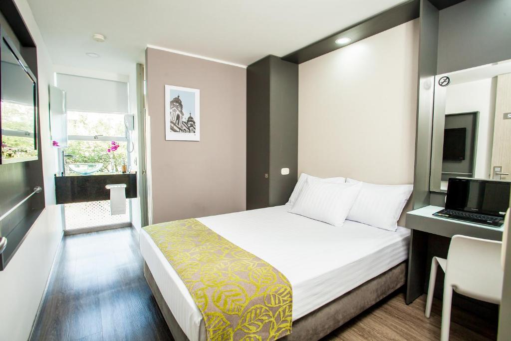 a bedroom with a bed and a desk with a laptop at Eco Star Hotel in Ibagué