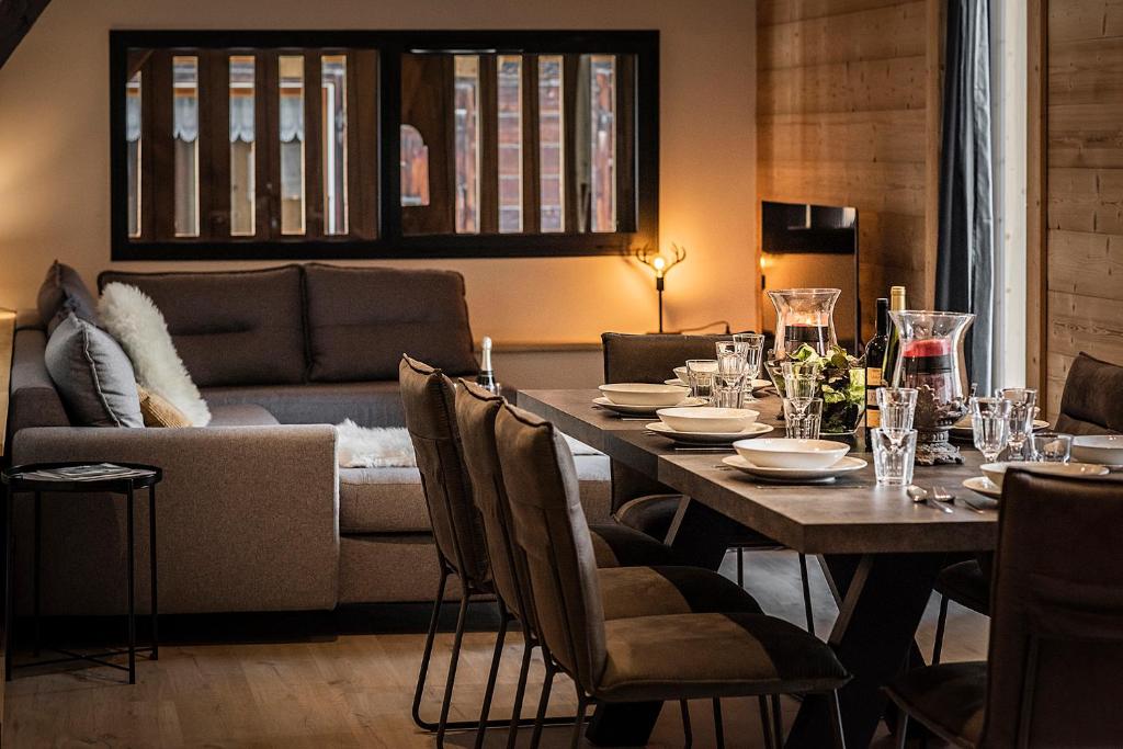 a dining room with a table and a couch at Nouveau et spacieux, Place de l'Eglise et terrasse privative in La Clusaz