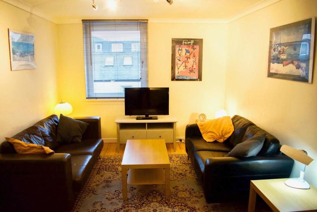a living room with two couches and a flat screen tv at Welcoming and Homely 2 Bed in Central Location in Edinburgh