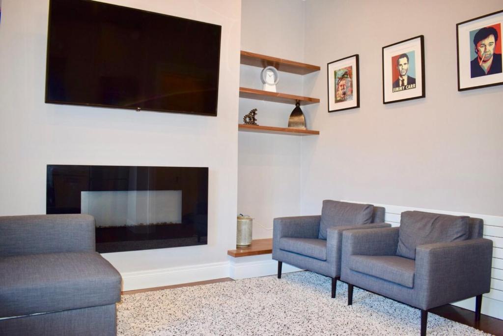 a living room with two chairs and a flat screen tv at Beautiful 2 Bedroom Ballsbridge Apartment near the Aviva in Dublin